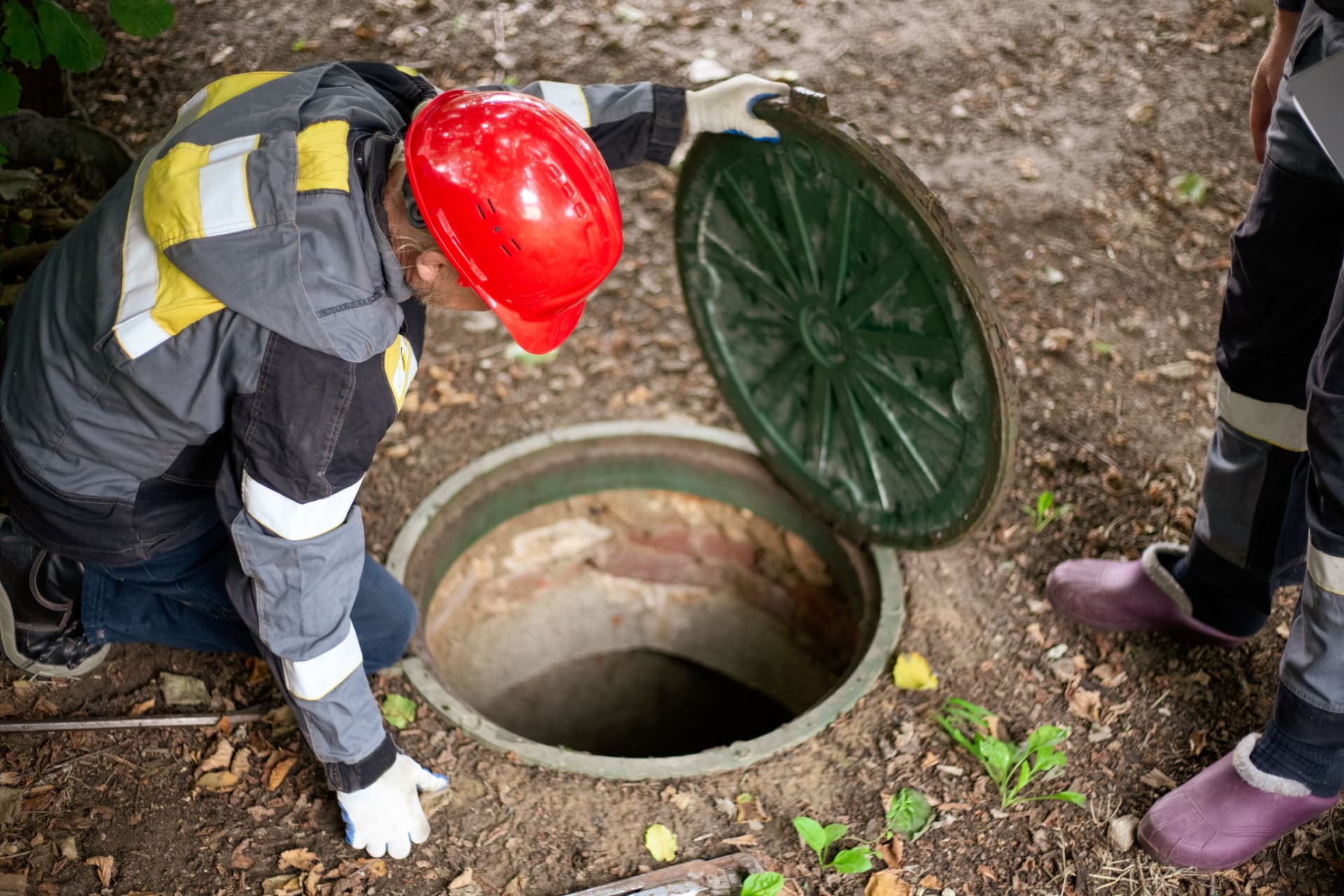 Workers lifting a tank access cover for inspection
