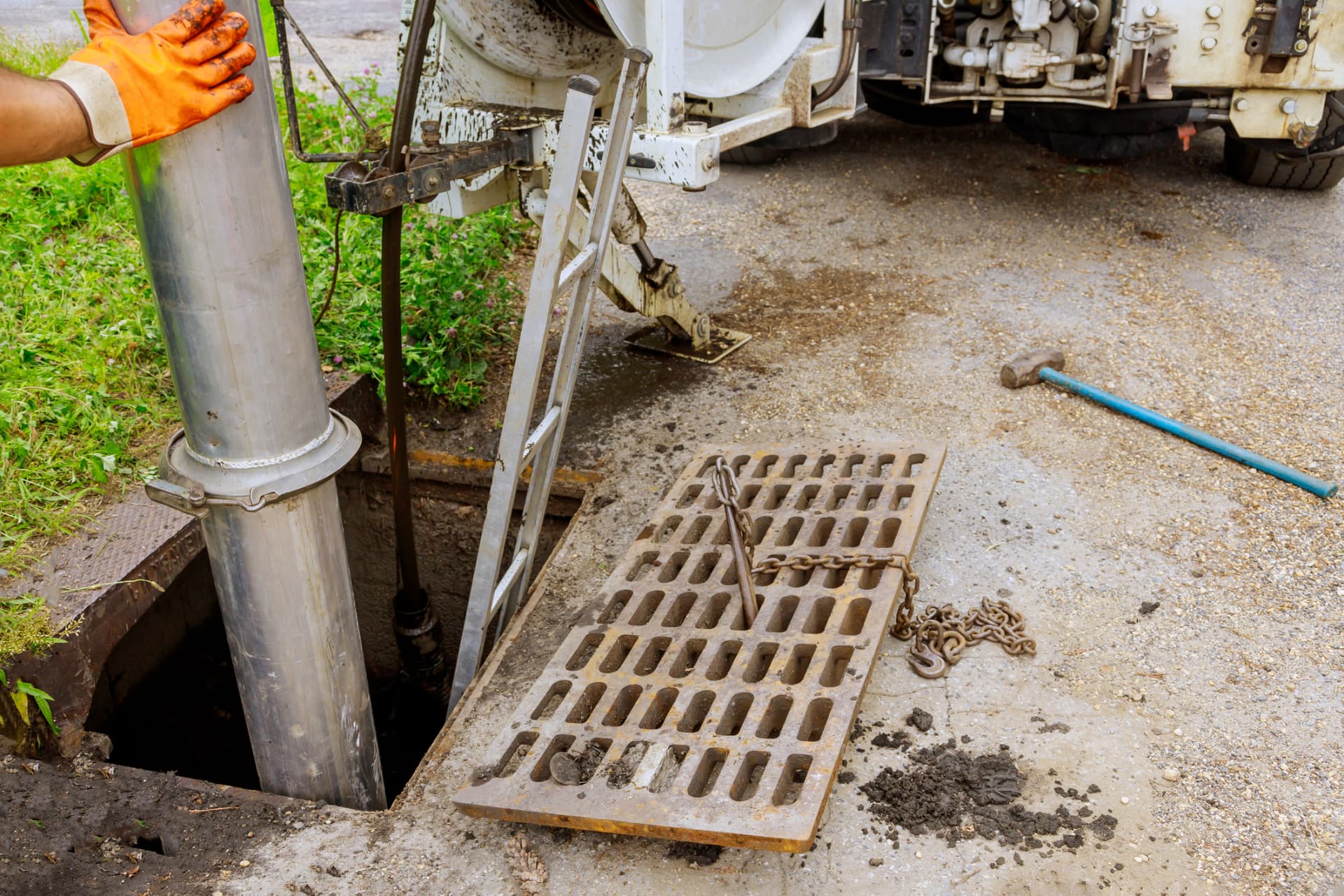 Suction pipe lowered into an access chamber beside a service truck