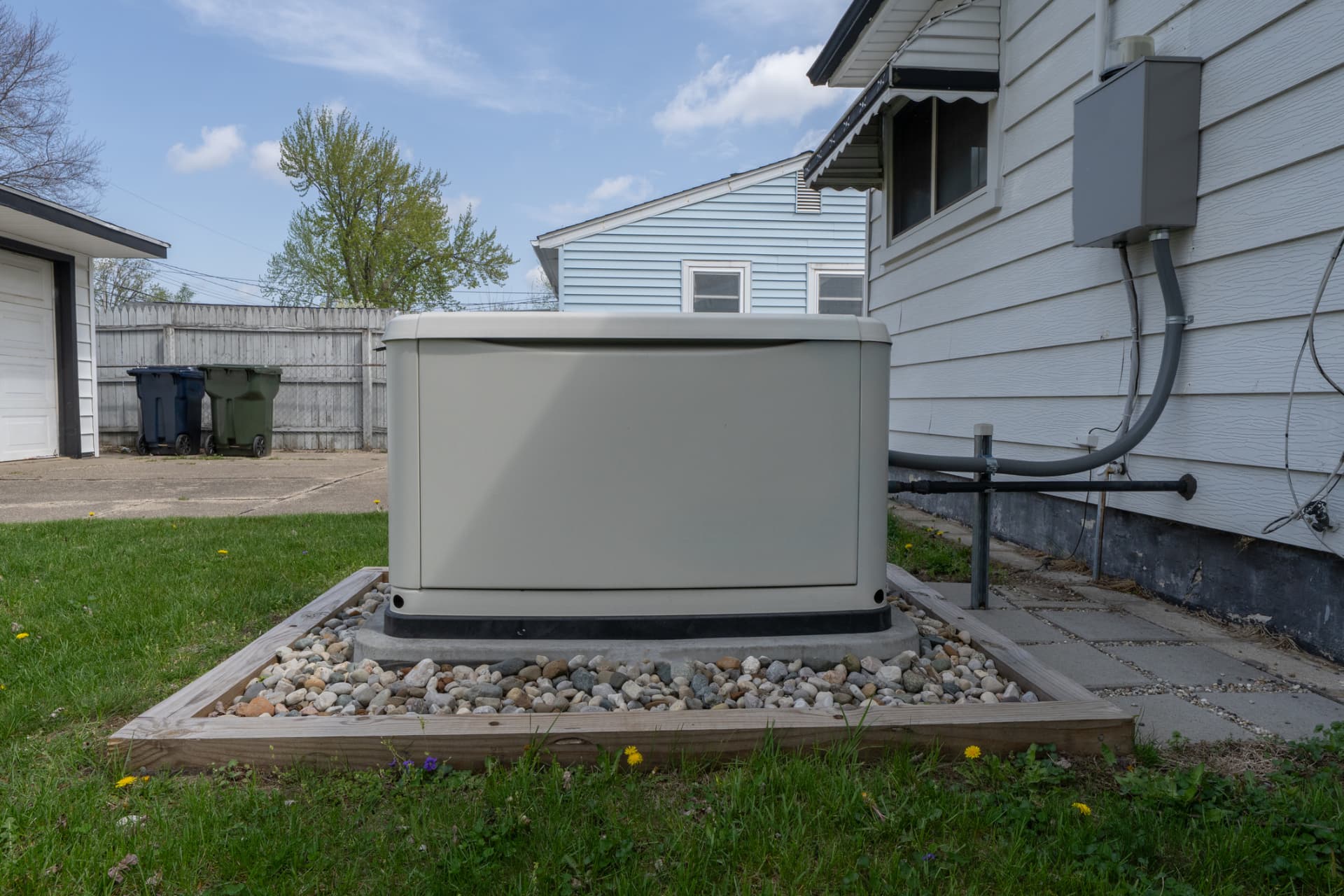 Residential standby generator on a concrete pad beside a house