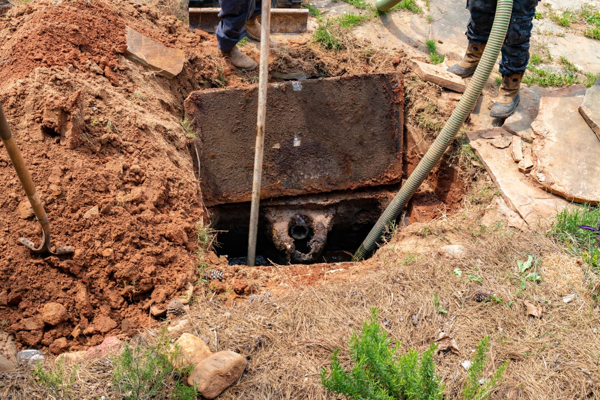 Excavated buried tank with suction hose during a clean-out