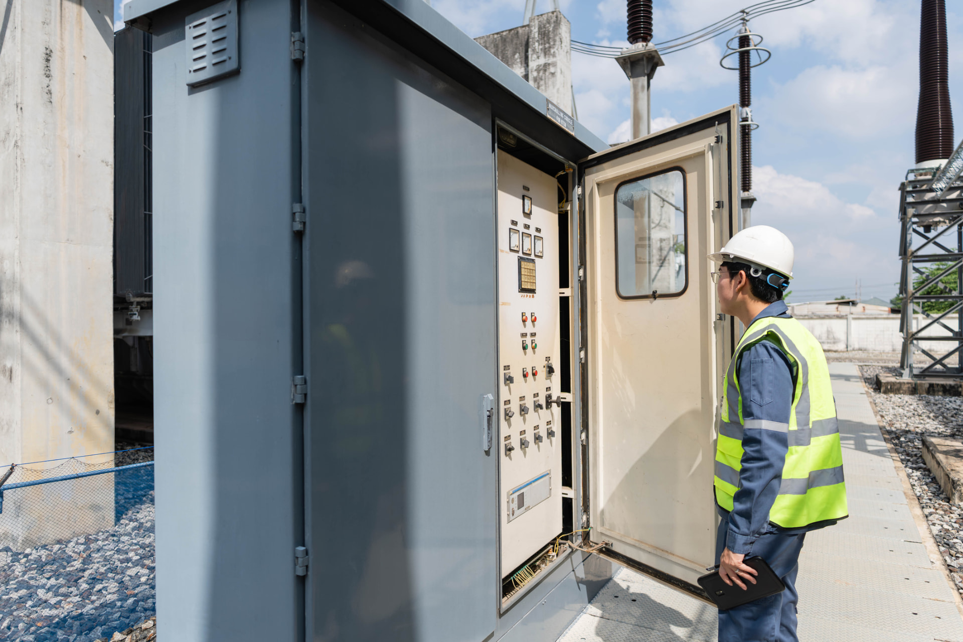 Engineer inspecting an open control cabinet at a substation