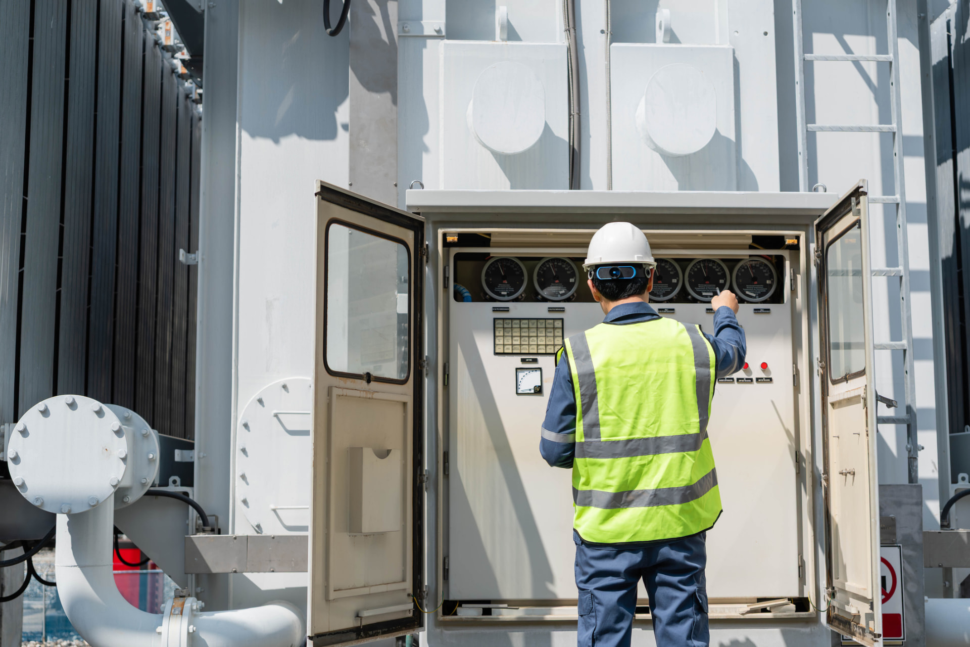 Technician checking gauges on an outdoor power control cabinet